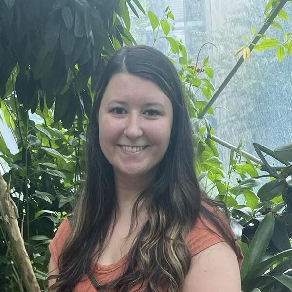Woman smiling while standing in front of multiple plants